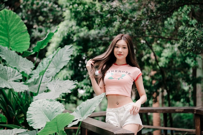 Asian woman in pink t-shirt and shorts posing outdoors