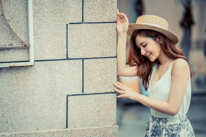 Asian woman with brown hair wearing a hat and white top