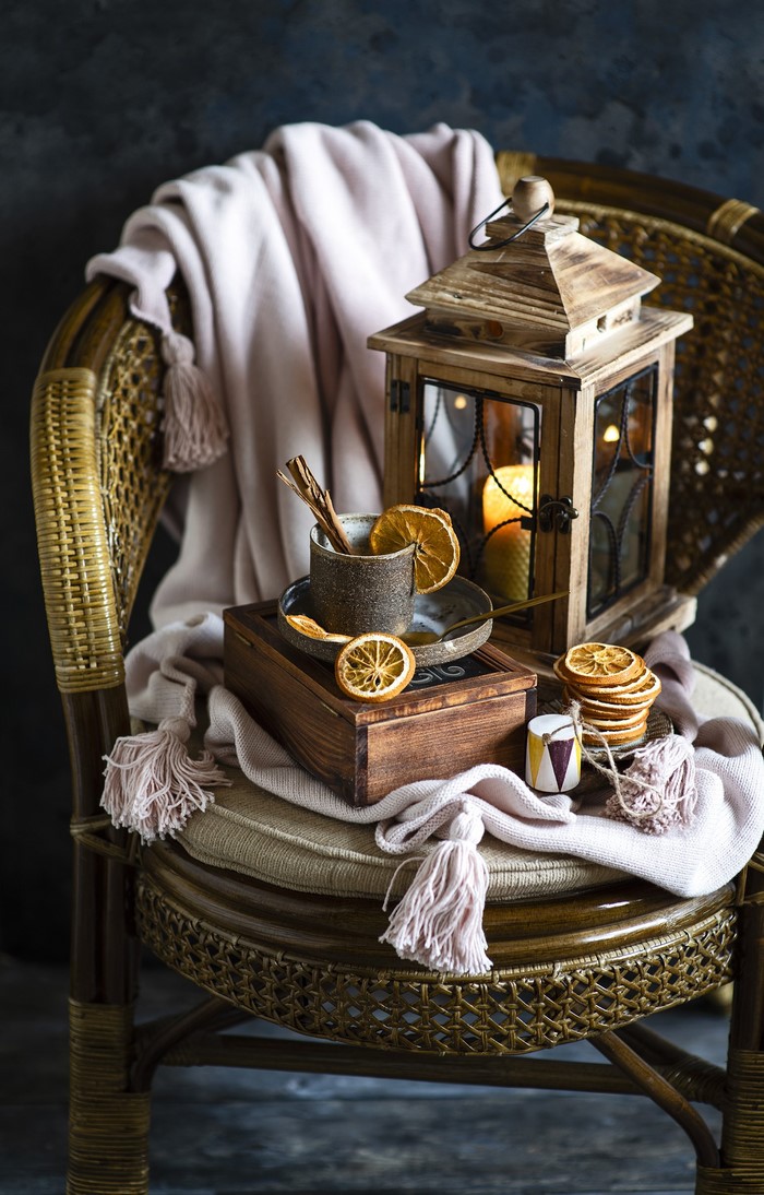 Still life with lantern, mug, and dried oranges on a chair