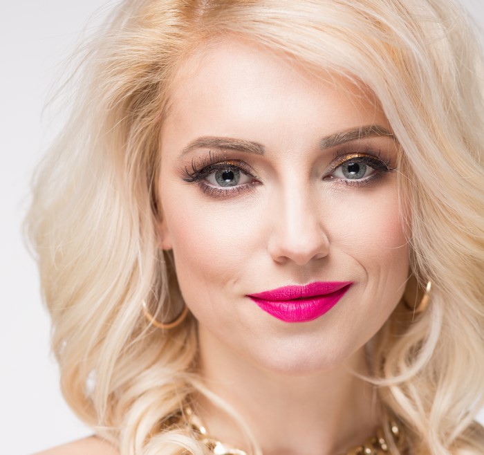 Blonde woman with bright pink lipstick and gold eyeshadow