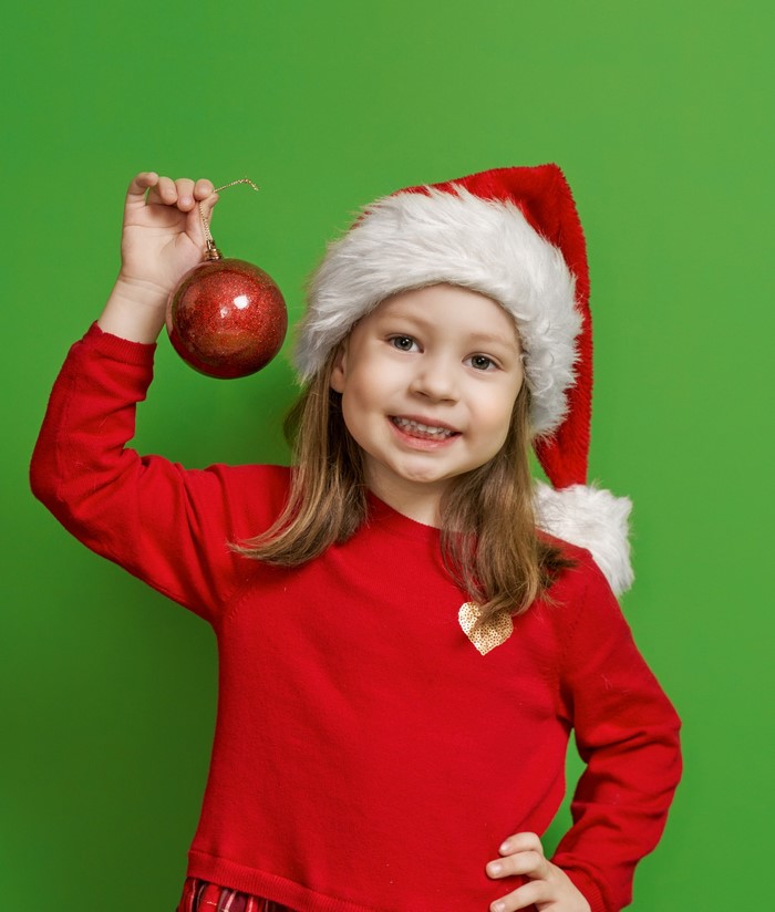 Girl in Santa hat holding Christmas ornament
