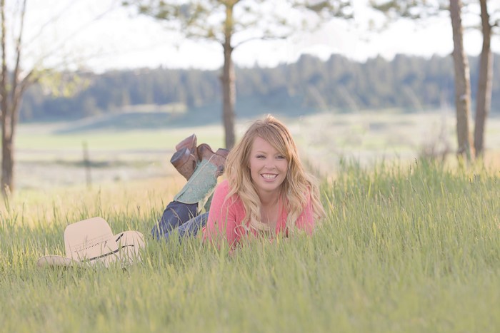 Blonde girl lying in grass with hat and boots