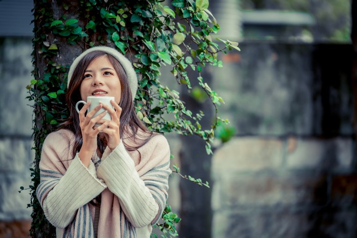 Asian woman holding a mug with ivy background