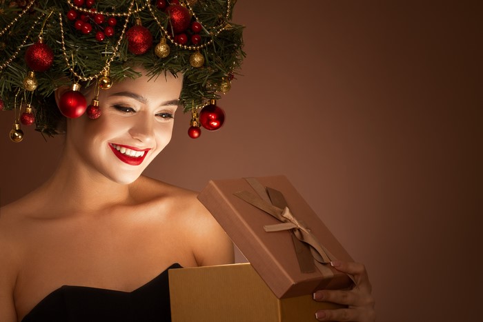 Woman with Christmas tree headdress opening a gift