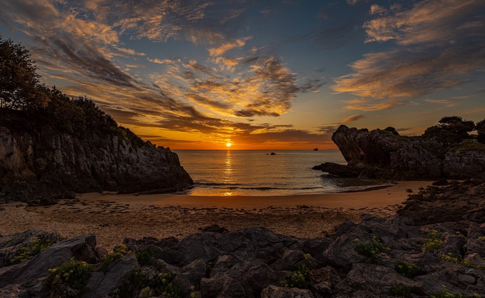 Sunset over a rocky beach with dramatic clouds