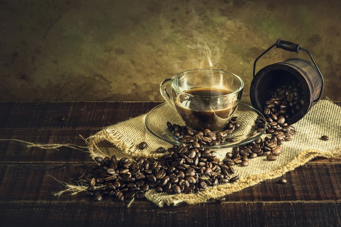 Coffee cup with steam and coffee beans