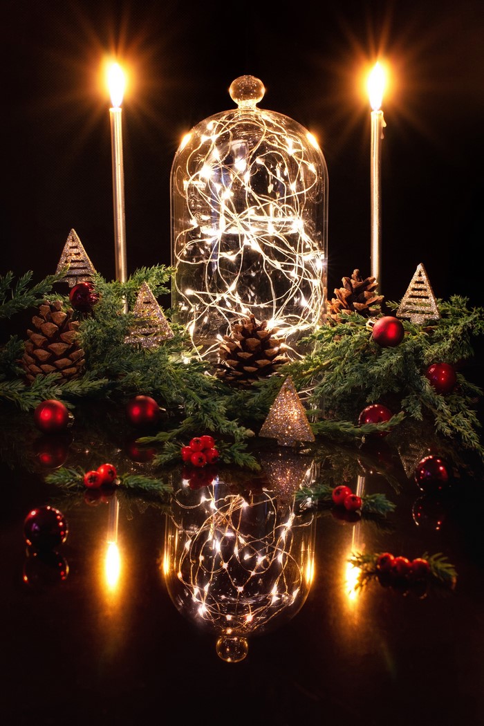 Christmas lights in a glass dome with candles and pine cones