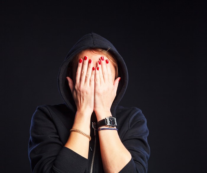 Woman in Hood Covering Face with Hands