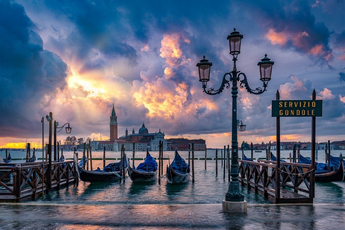 Venice gondolas at sunset with dramatic clouds