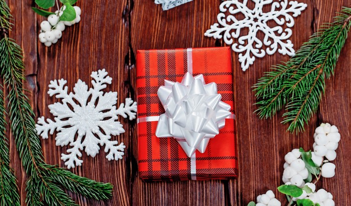 Christmas gift with snowflakes and pine branches on wood