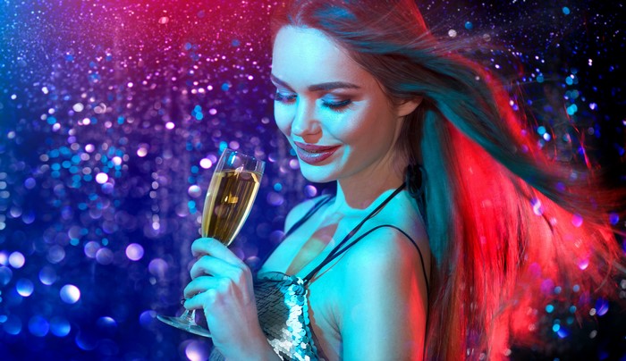 Woman holding champagne with glitter background