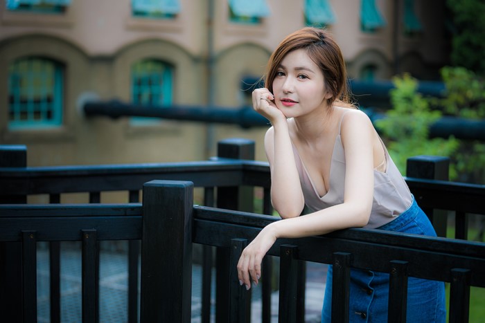 Asian woman with brown hair posing by a railing
