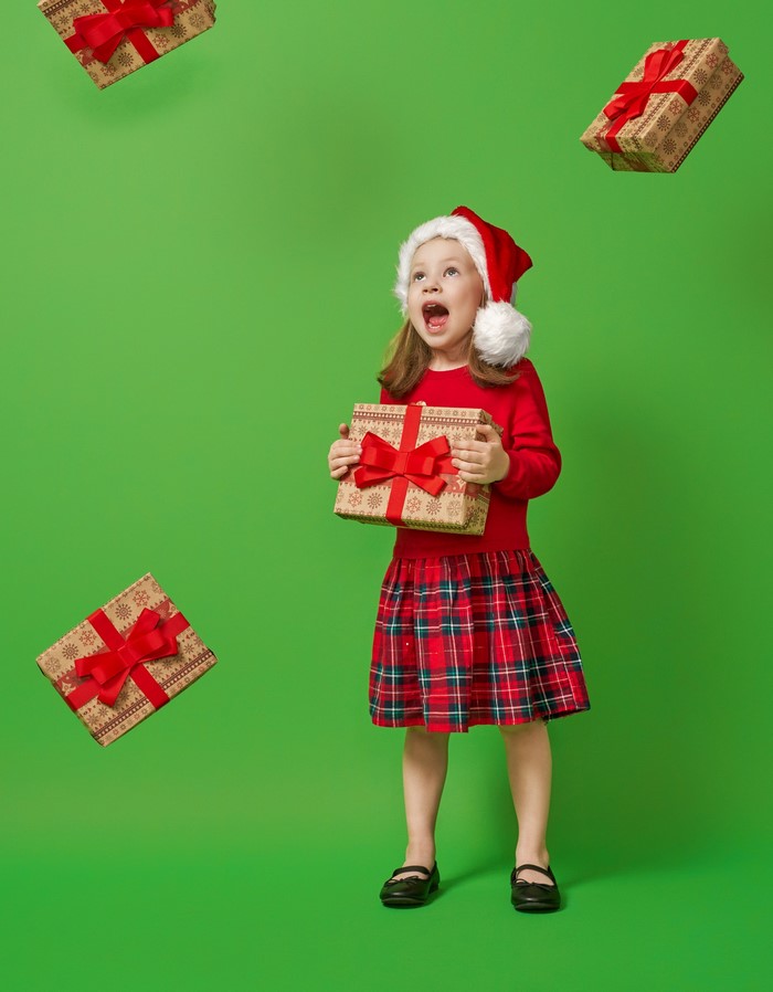 Girl in Santa hat with falling Christmas gifts