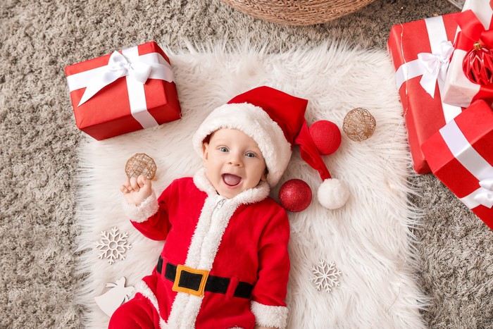 Baby in Santa costume with Christmas gifts