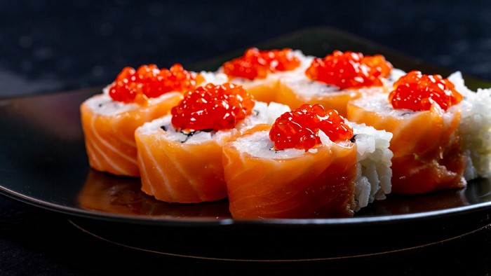 Sushi with salmon and caviar on a black plate