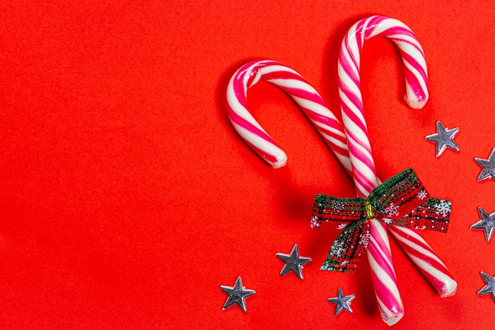 Christmas candy canes with bow and stars on red background