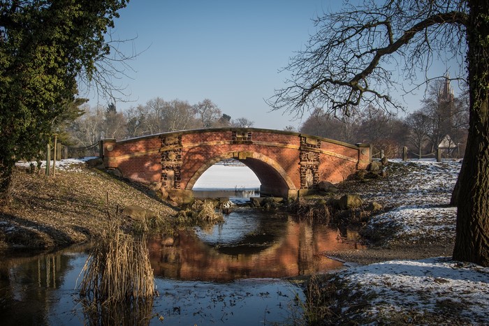 Brick bridge over a frozen stream in a park during winter