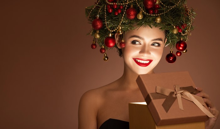 Woman with Christmas tree headdress opening a gift