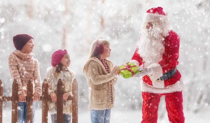 Santa Claus giving a gift to children in the snow