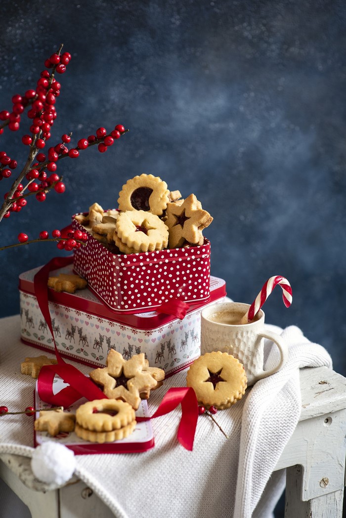 Christmas cookies in festive tins with coffee and holly