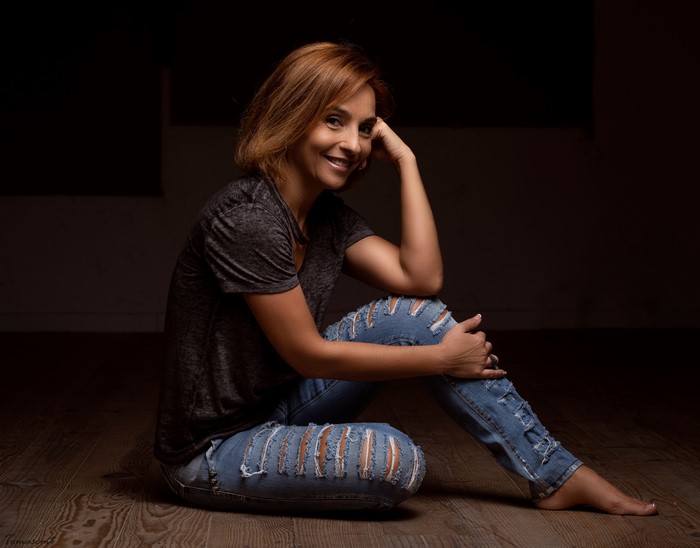 Adult woman with red hair sitting on floor in ripped jeans