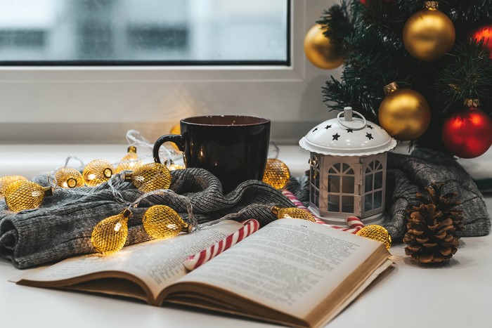 Christmas still life with book, mug, and fairy lights