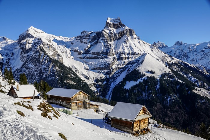 4K Winter scene in the Swiss Alps with snow-covered mountains and wooden houses