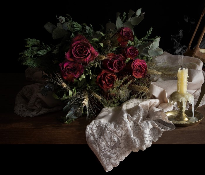 Still-life of dried roses and a lit candle