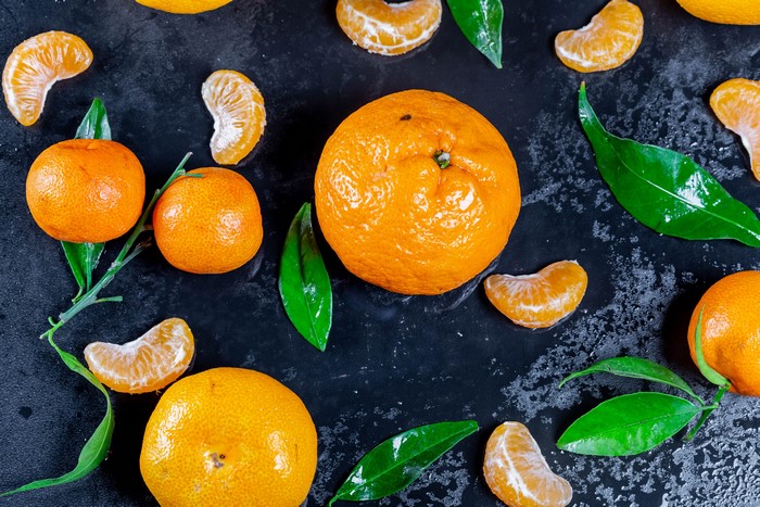 Tangerines and leaves on a dark surface
