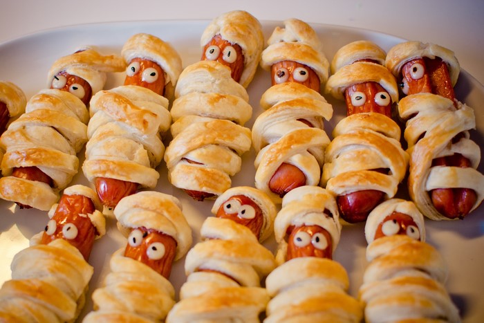 Mummy hot dogs with candy eyes on a platter