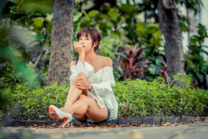 Asian woman with brown hair sitting in a park