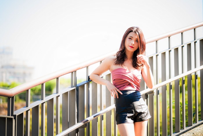 Asian woman in pink top and black shorts posing on stairs