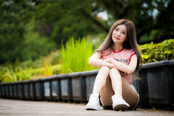 Asian girl with brown hair sitting outdoors