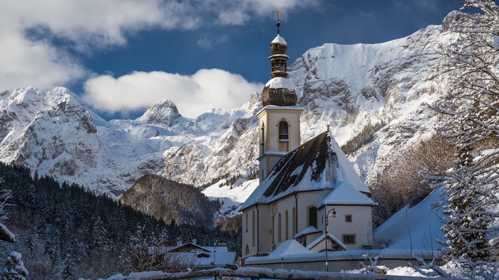 St. Sebastian church in Ramsau, Germany, with snowy mountains