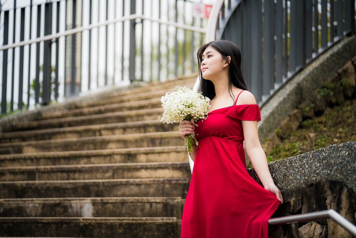 Woman in red dress holding a bouquet on stairs