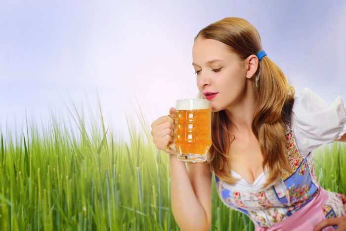 Woman in Dirndl holding a beer mug in a field