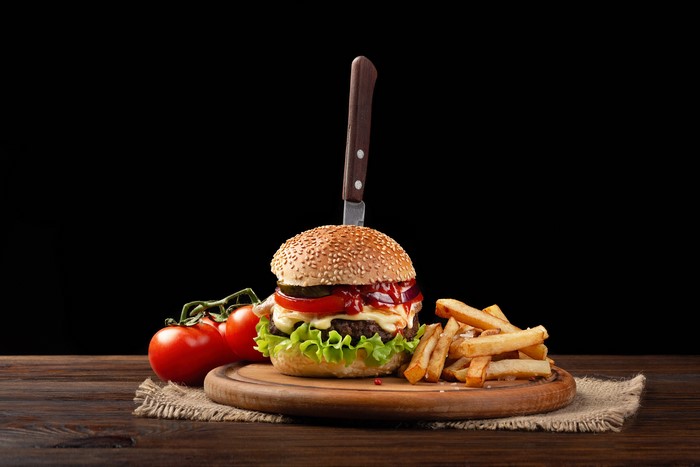 Hamburger with fries and tomatoes on a cutting board