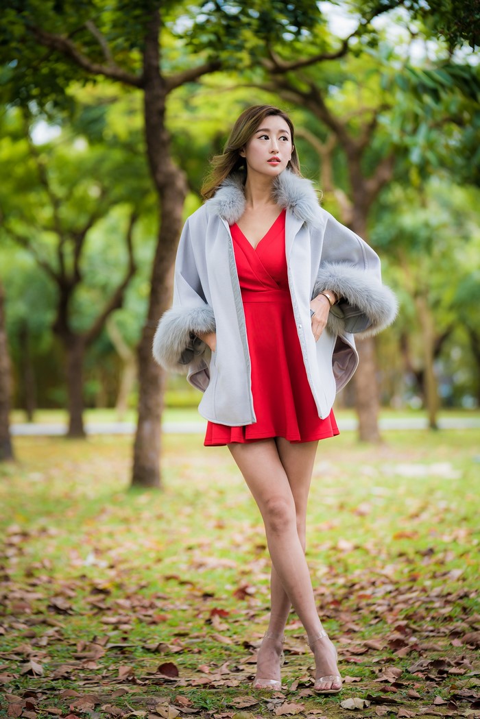 Asian woman in red dress and grey coat in park