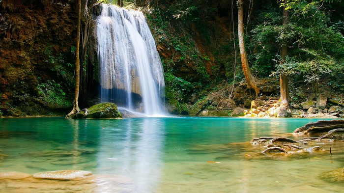 Waterfall cascading into a turquoise pool in a lush forest
