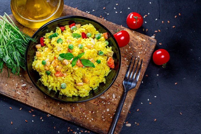 Yellow rice with vegetables and tomatoes on a cutting board