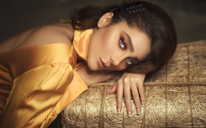Brunette woman with makeup resting on hay bale