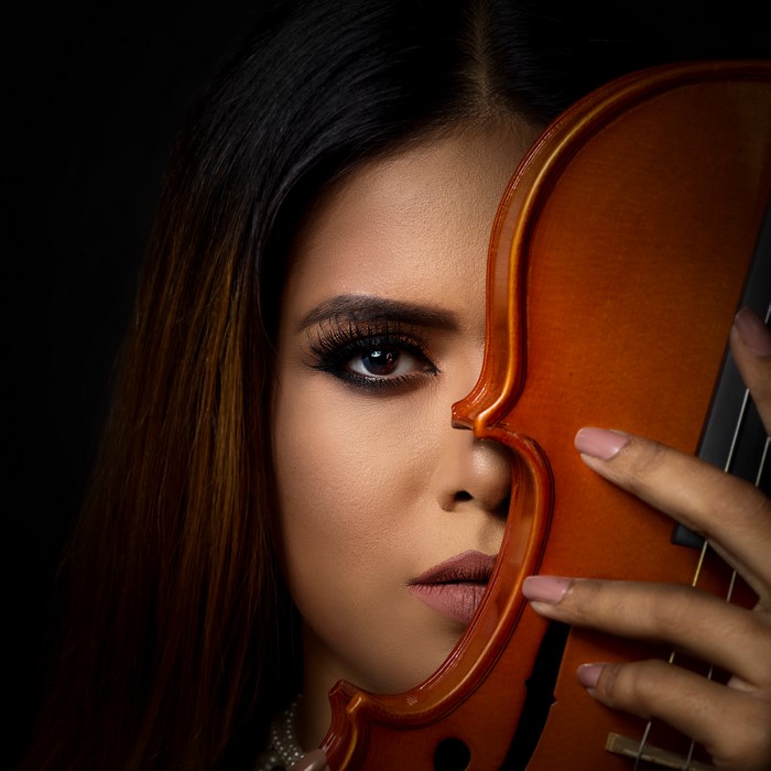 Woman with violin and makeup on black background