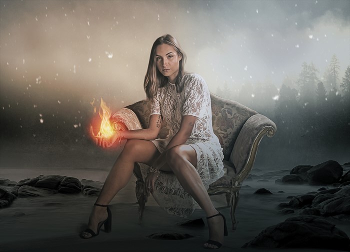 Woman with fire in her hands sitting on an armchair