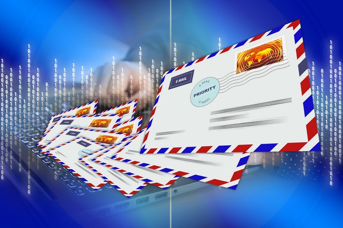 Many postal envelopes on a laptop with binary code background