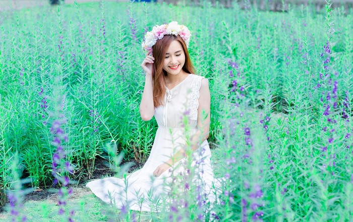 Asian woman with flower wreath in field
