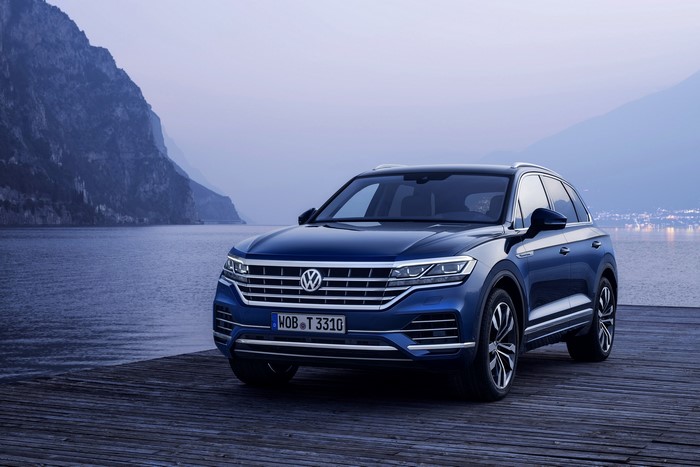 Blue Volkswagen Touareg SUV on a wooden pier by a lake