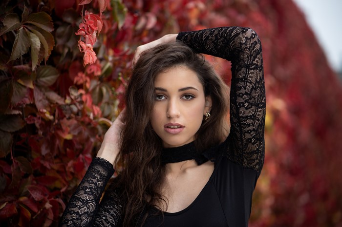 Woman with hands in hair near red leaves