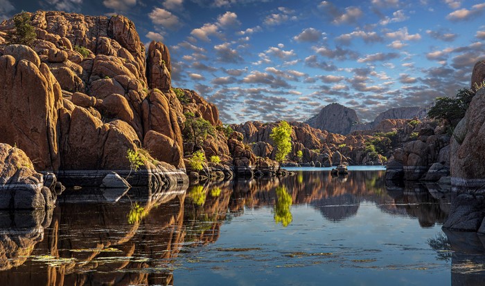 Rocky lake shore with reflections under a cloudy sky