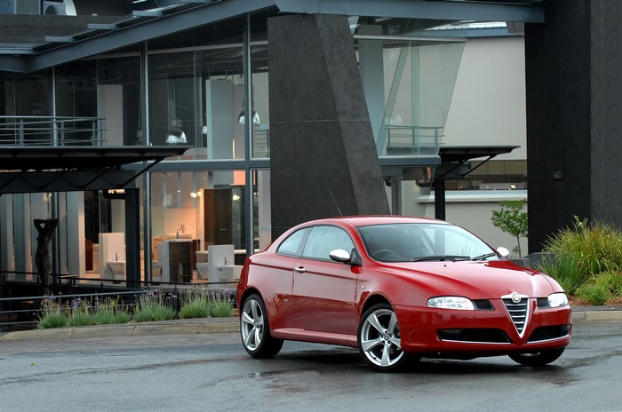 Red Alfa Romeo GT Coupe in front of modern building