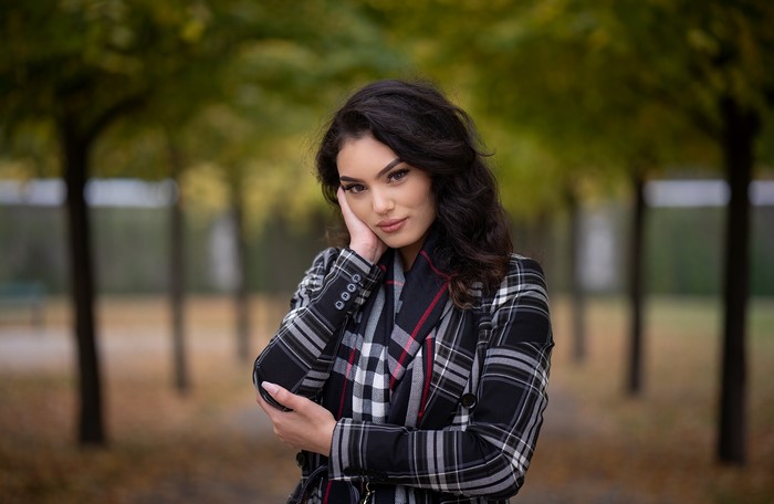 Brunette girl in plaid coat posing outdoors